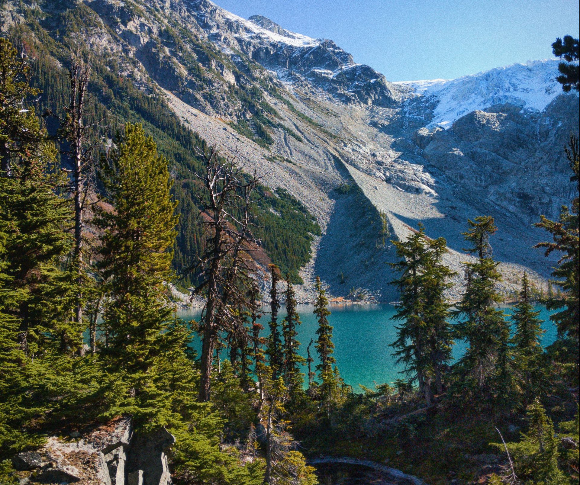 rocky mountains with blue-green lake and coniferous trees